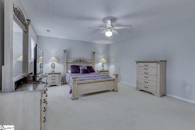 bedroom with ceiling fan, light colored carpet, and a textured ceiling