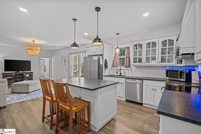 kitchen featuring white cabinetry, stainless steel appliances, a center island, and sink