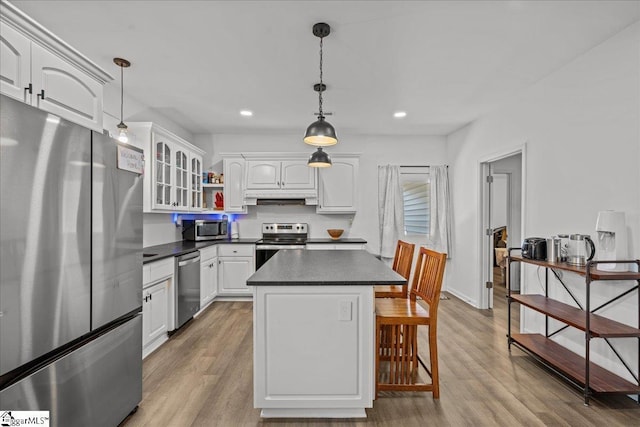 kitchen featuring appliances with stainless steel finishes, decorative light fixtures, a center island, and white cabinets