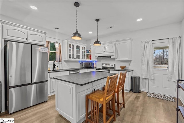 kitchen with white cabinetry, appliances with stainless steel finishes, sink, and decorative light fixtures