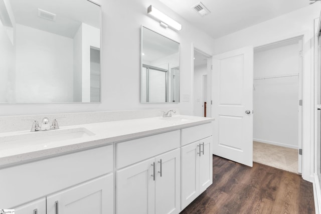 bathroom with hardwood / wood-style flooring, vanity, and a shower with shower door