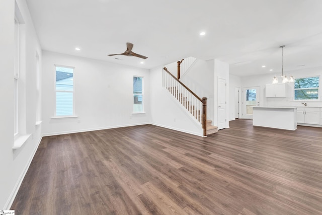 unfurnished living room with dark hardwood / wood-style flooring and ceiling fan with notable chandelier