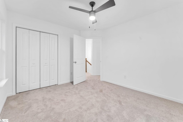 unfurnished bedroom featuring light carpet, ceiling fan, and a closet