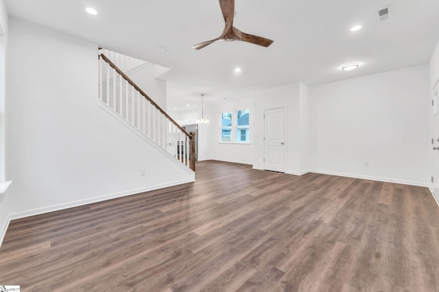 unfurnished living room featuring dark wood-type flooring and ceiling fan with notable chandelier