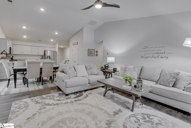 living room featuring lofted ceiling, ceiling fan, and light wood-type flooring