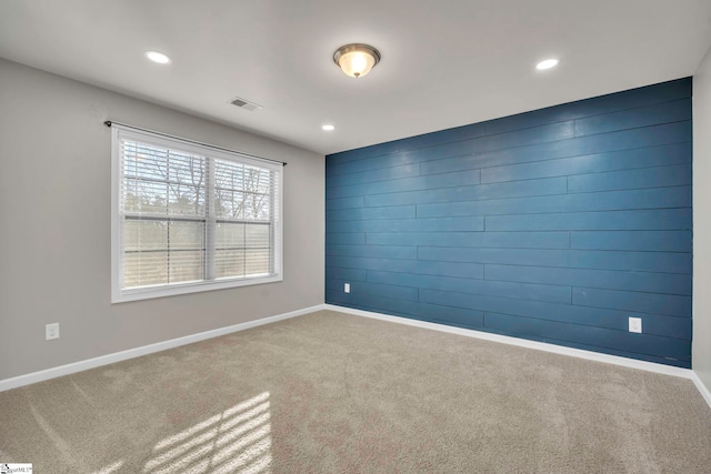 carpeted spare room with wood walls