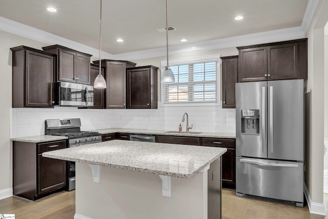 kitchen featuring a kitchen island, pendant lighting, sink, a kitchen breakfast bar, and stainless steel appliances