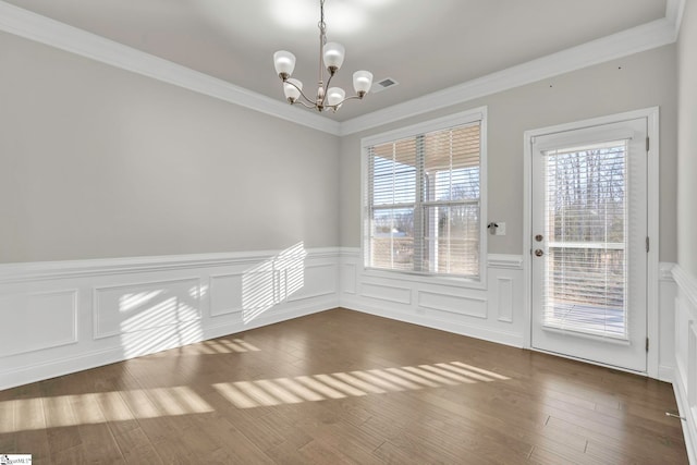 unfurnished dining area with ornamental molding, dark wood-type flooring, and a notable chandelier