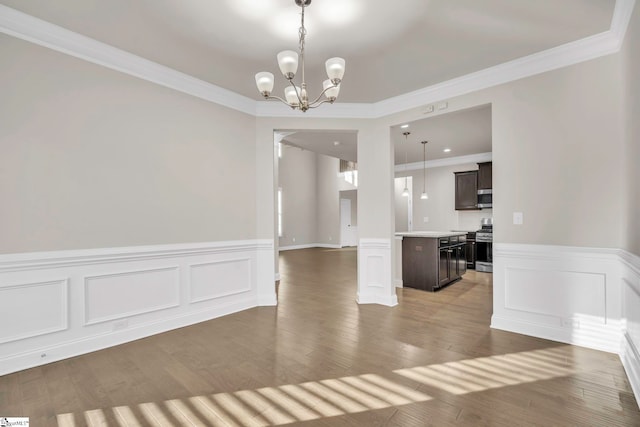 empty room featuring an inviting chandelier, crown molding, and wood-type flooring