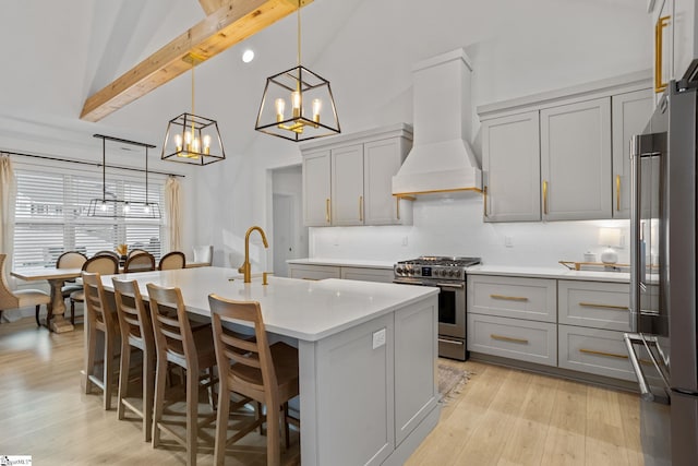 kitchen featuring gray cabinets, premium range hood, hanging light fixtures, high end appliances, and an island with sink