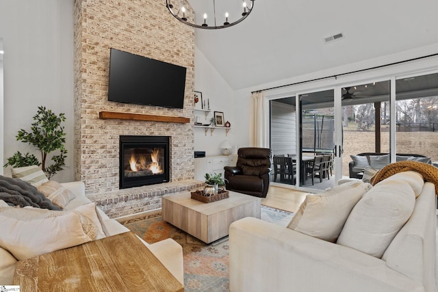 living room featuring a brick fireplace, a notable chandelier, high vaulted ceiling, and light wood-type flooring