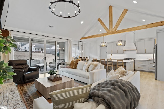 living room with beamed ceiling, an inviting chandelier, high vaulted ceiling, and light hardwood / wood-style flooring