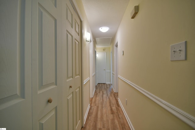 hallway featuring a textured ceiling and light hardwood / wood-style flooring