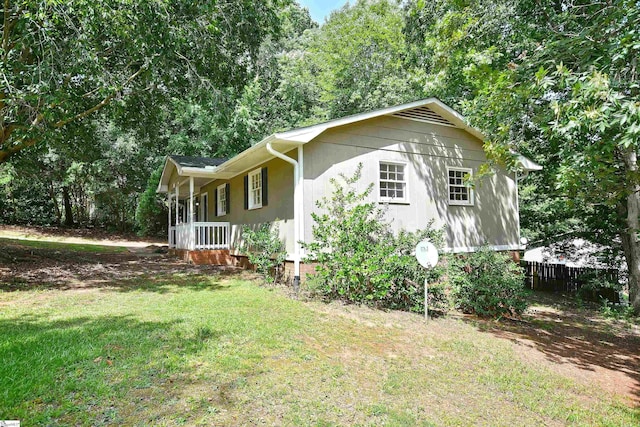 view of side of property with covered porch and a lawn