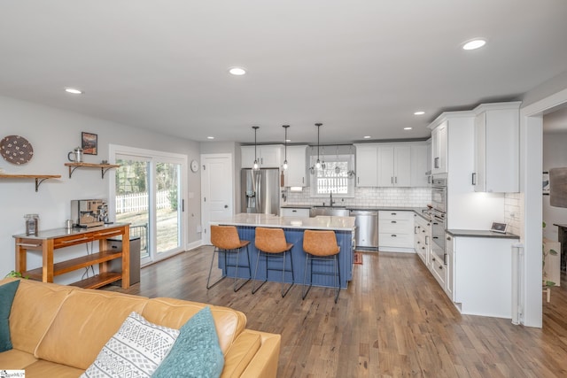 kitchen featuring white cabinetry, decorative light fixtures, stainless steel appliances, and a center island