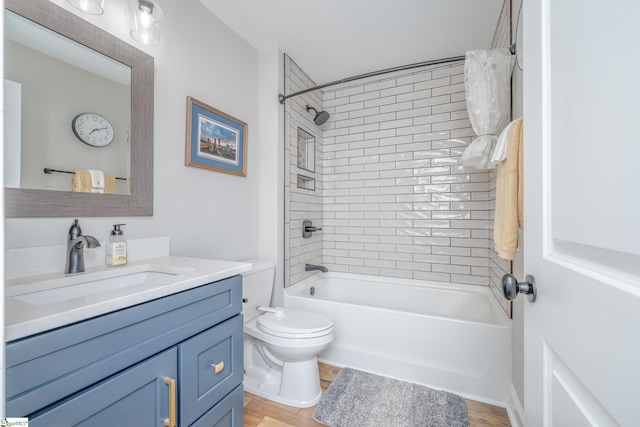 full bathroom featuring vanity, tiled shower / bath combo, and toilet