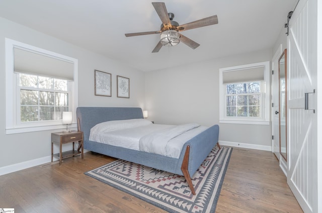 bedroom with hardwood / wood-style floors, a barn door, and ceiling fan