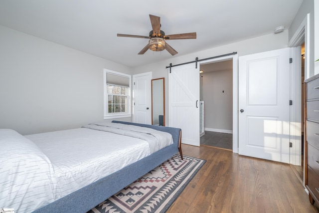 bedroom featuring dark hardwood / wood-style flooring, a barn door, and ceiling fan