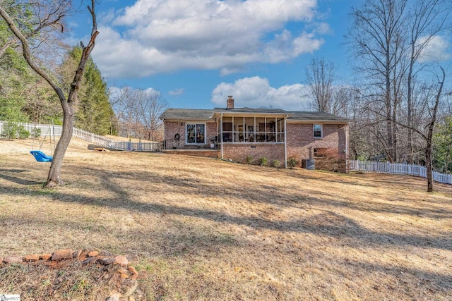 view of front facade with central AC, a sunroom, and a front yard