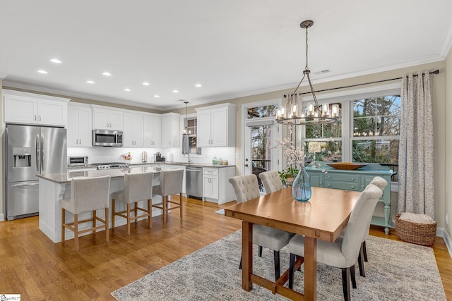 dining room with ornamental molding, plenty of natural light, sink, and light hardwood / wood-style floors