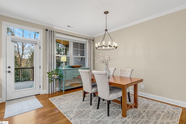 dining room with an inviting chandelier, ornamental molding, and hardwood / wood-style floors