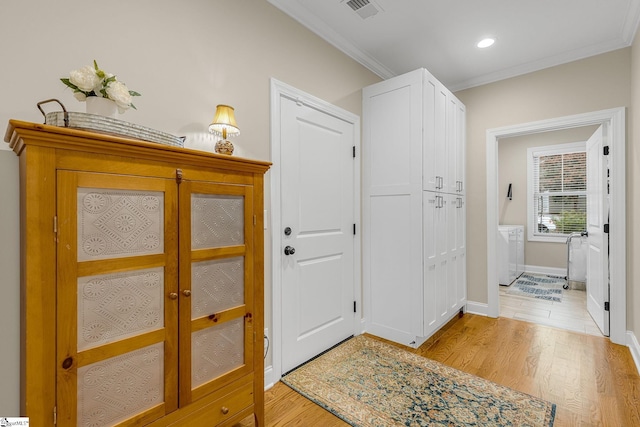 entrance foyer with crown molding, washer / dryer, and light hardwood / wood-style flooring