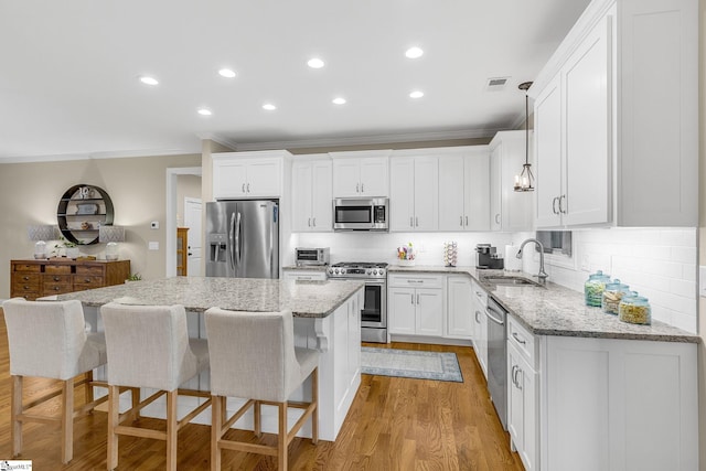 kitchen with appliances with stainless steel finishes, decorative light fixtures, a center island, and white cabinets