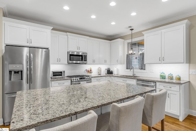 kitchen with white cabinetry, sink, ornamental molding, a center island, and stainless steel appliances