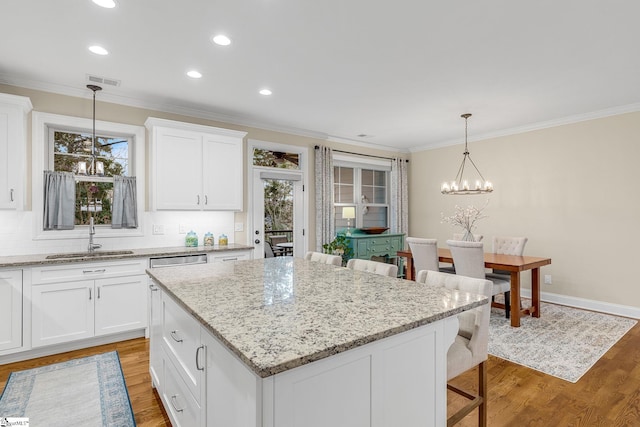 kitchen with pendant lighting, sink, a kitchen island, and white cabinets