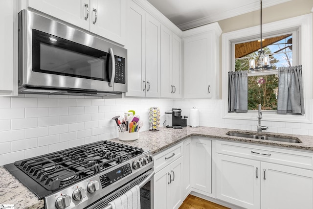 kitchen featuring light stone counters, sink, stainless steel appliances, and white cabinets