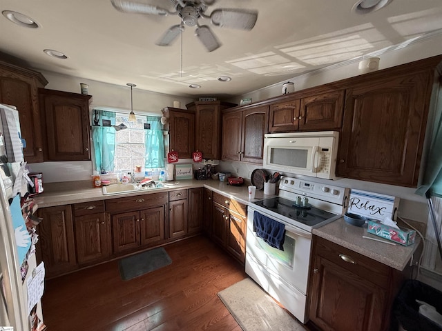 kitchen with dark wood-type flooring, sink, decorative light fixtures, ceiling fan, and white appliances