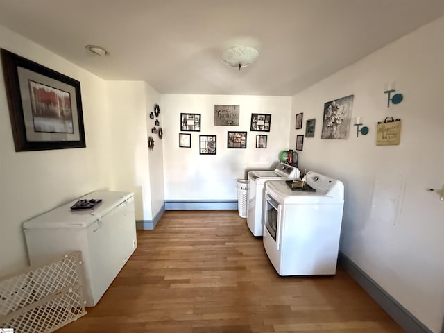 clothes washing area featuring a baseboard radiator, washer and dryer, and light hardwood / wood-style flooring