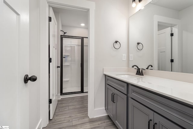 bathroom featuring hardwood / wood-style flooring, vanity, and an enclosed shower