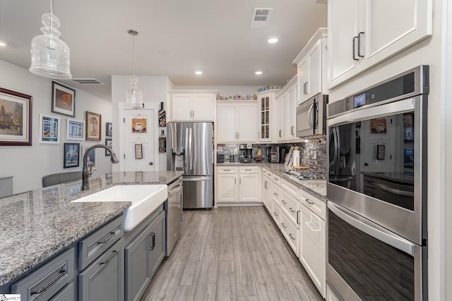 kitchen featuring sink, hanging light fixtures, appliances with stainless steel finishes, gray cabinets, and white cabinets