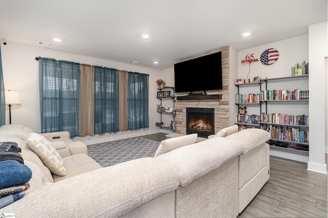 living room with hardwood / wood-style flooring and a stone fireplace