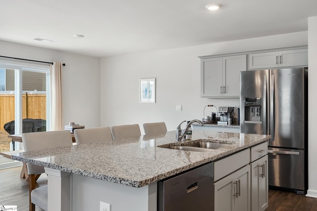 kitchen featuring stainless steel fridge, dishwasher, sink, and a center island with sink