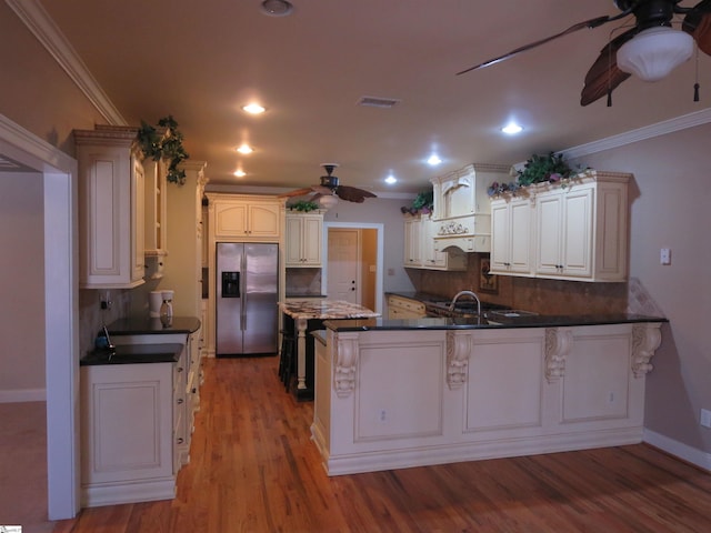 kitchen featuring light hardwood / wood-style flooring, stainless steel fridge, ceiling fan, ornamental molding, and kitchen peninsula