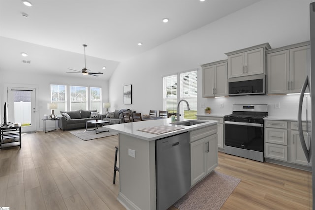 kitchen with gray cabinets, an island with sink, sink, stainless steel appliances, and a healthy amount of sunlight