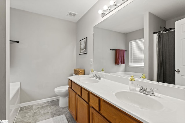 bathroom with a washtub, vanity, and toilet