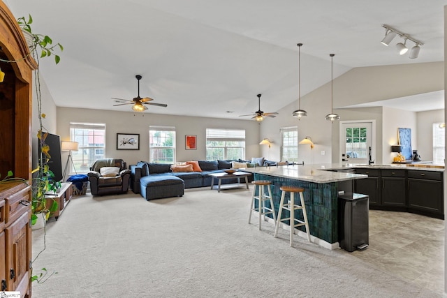 kitchen with a breakfast bar, hanging light fixtures, a kitchen island, a wealth of natural light, and light stone countertops