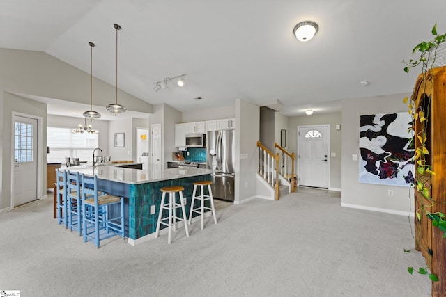 kitchen with appliances with stainless steel finishes, a breakfast bar, white cabinets, hanging light fixtures, and light stone countertops