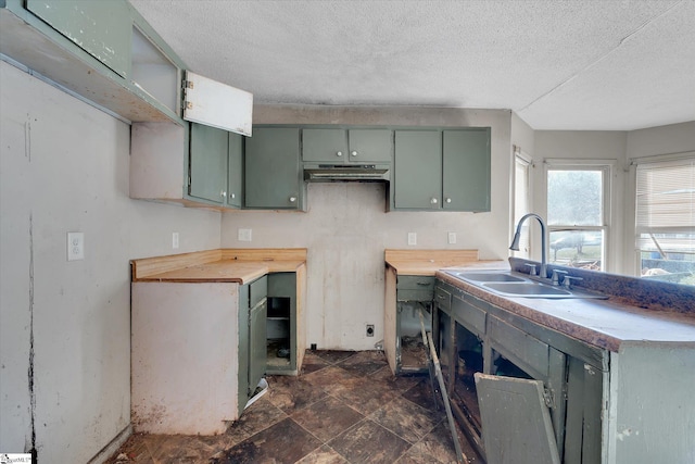 kitchen featuring sink, a textured ceiling, wooden counters, and green cabinetry