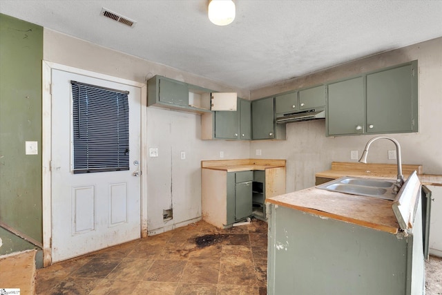 kitchen featuring green cabinetry, sink, and a textured ceiling