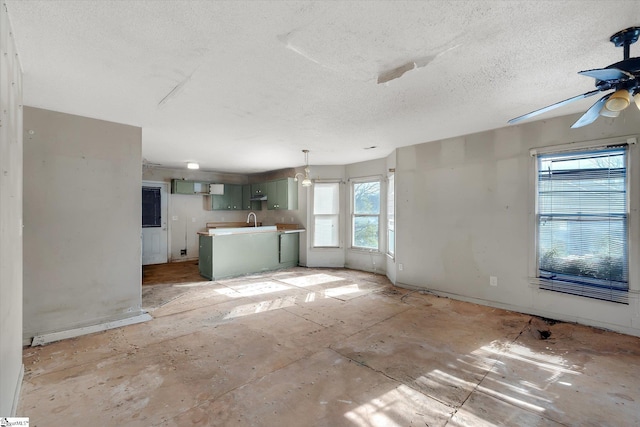 unfurnished living room with ceiling fan, sink, and a textured ceiling