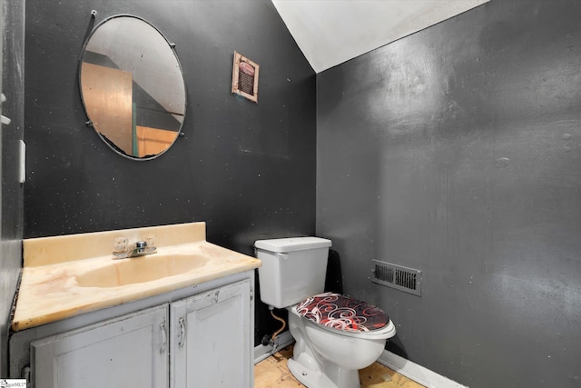 bathroom featuring vanity, toilet, and vaulted ceiling