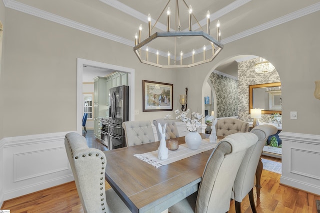 dining space featuring an inviting chandelier, ornamental molding, and light hardwood / wood-style floors