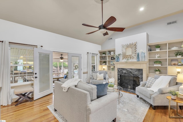 living room with vaulted ceiling, ceiling fan, a premium fireplace, and light hardwood / wood-style floors