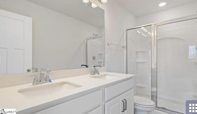 bathroom featuring vanity, toilet, and a shower with door