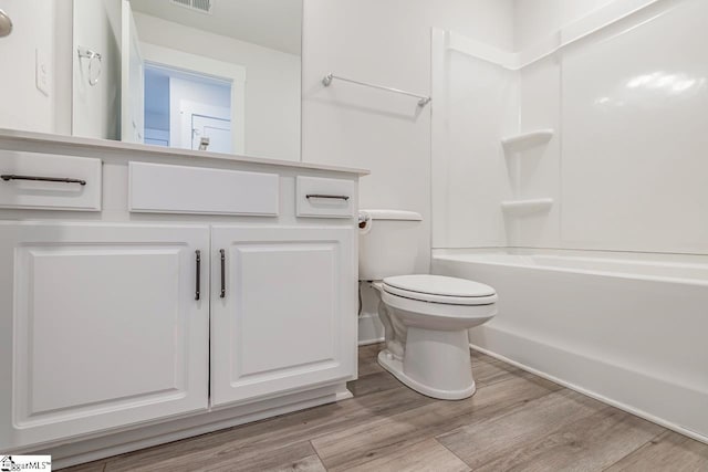 full bathroom with vanity, hardwood / wood-style flooring,  shower combination, and toilet