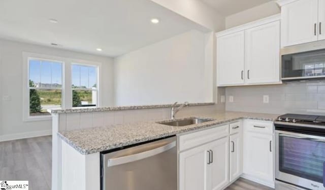 kitchen featuring white cabinetry, stainless steel appliances, kitchen peninsula, and sink